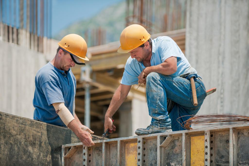 Dwóch pracowników budowlanych montujących betonowe ramy szalunkowe