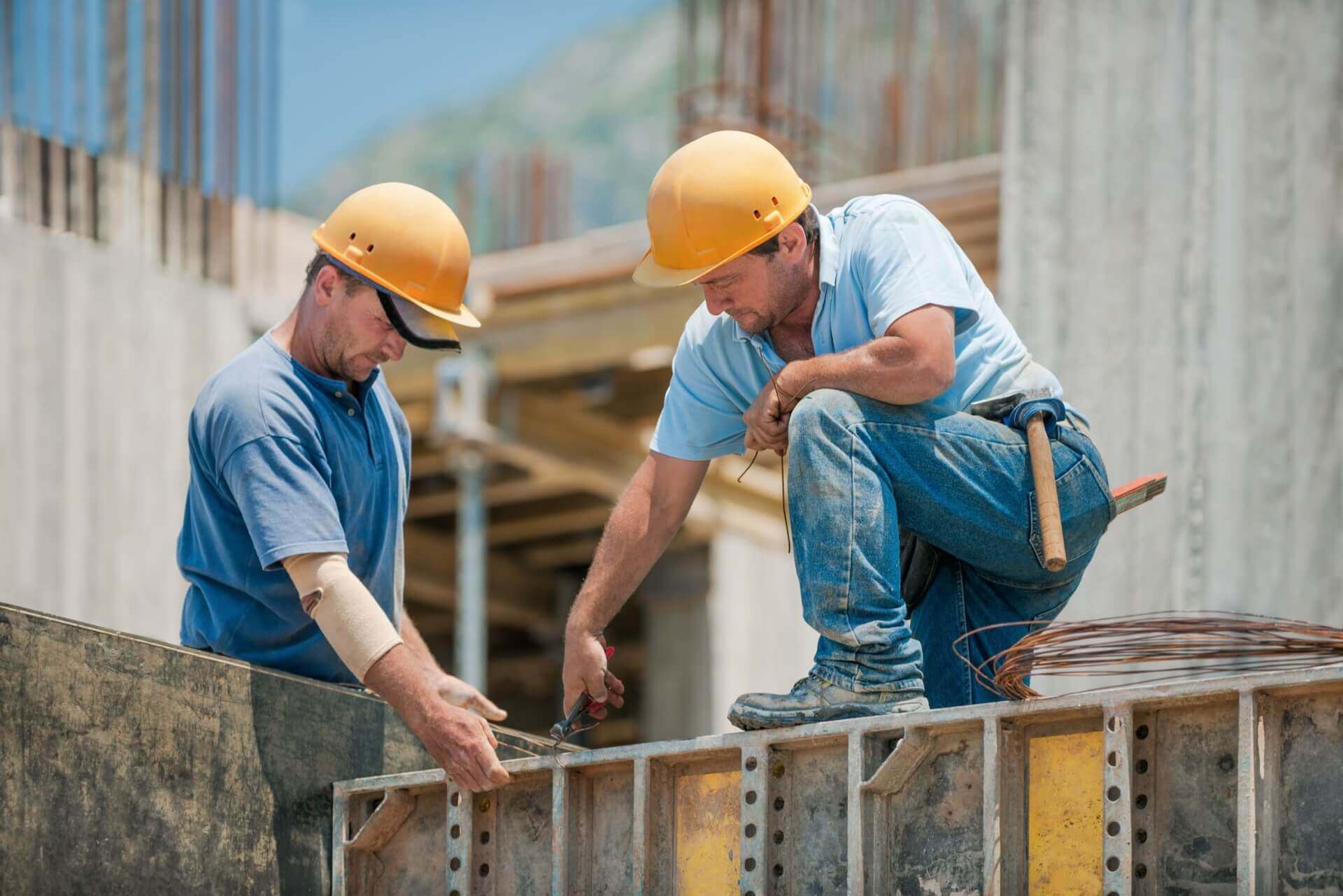 Two construction workers installing concrete formwork frames